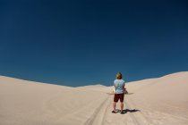 Visão traseira do homem com sandboard em pé no deserto — Fotografia de Stock