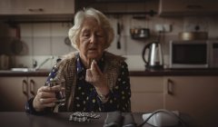 Senior mulher tendo pílula na cozinha em casa — Fotografia de Stock