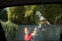 Boy washing a car at outside garage on a sunny day — Stock Photo