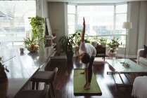 Молода жінка виконує йогу на йозі мат вдома — стокове фото