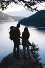 Rear view of couple with bag pack standing on rock — Stock Photo
