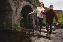Casal feliz correndo no caminho de pedra no rio — Fotografia de Stock