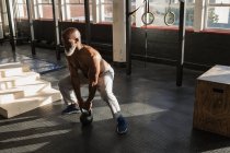 Решительный старший человек упражнения с гирями в фитнес-студии . — стоковое фото