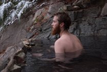 Thoughtful man relaxing in hot spring during winter — Stock Photo