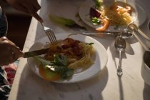 Primo piano delle mani femminili che mangiano pasta con verdure a tavola . — Foto stock