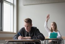 Дівчина-підліток піднімає руку в класі в університеті — стокове фото