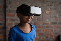 Счастливая девочка-подросток, использующая гарнитуру виртуальной реальности в офисе . — стоковое фото