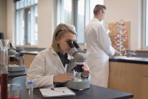Ragazza adolescente che sperimenta al microscopio in laboratorio all'università — Foto stock