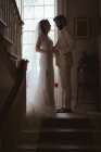 Bride and groom holding hands on the steps at home — Stock Photo