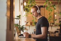 Mann hört Musik über Kopfhörer während Handy im Café — Stockfoto
