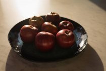 Яблука на керамічному лотку за кухонним столом . — стокове фото
