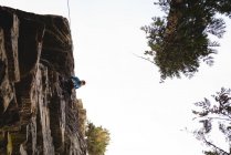 Randonneur se préparant à escalader la montagne rocheuse en forêt — Photo de stock