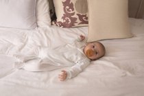 Cute little baby with pacifier in mouth sleeping on bed at home — Stock Photo