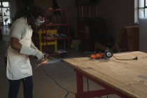 Carpintería de corte de metal con sierra eléctrica en taller - foto de stock