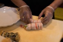 Chef preparando sushi em uma tábua de corte na cozinha — Fotografia de Stock