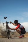 Motociclista revisando su bicicleta de montaña en la carretera en un día soleado - foto de stock