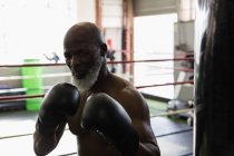 Determinado homem sênior boxe no ringue de boxe . — Fotografia de Stock
