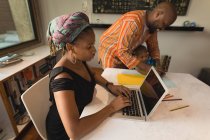 Женщина использует ноутбук, пока отец помогает сыну рисовать дома . — стоковое фото