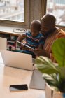 Feliz padre e hijo usando tableta digital en la mesa con el ordenador portátil . - foto de stock