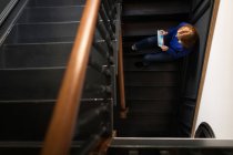 Über den Kopf einer Frau, die auf der Treppe sitzt und ein Tablet benutzt — Stockfoto