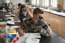 Estudantes universitários experimentando microscópio em laboratório na universidade — Fotografia de Stock