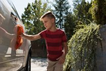 Хлопчик миє машину в гаражі в сонячний день — стокове фото