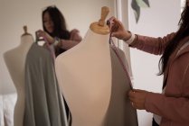 Fashion designer measuring fabric on mannequin at design studio. — Stock Photo