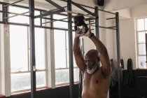Homme âgé déterminé à faire de l'exercice avec kettlebell dans un studio de fitness . — Photo de stock