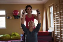 Жіночий терапевт, який допомагає старшій жінці з гантелями в будинку престарілих — стокове фото