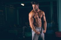 Мускулистый человек демонстрирует мышцы в фитнес-студии — стоковое фото