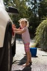 Братья и сестры моют машину в гараже на улице в солнечный день — стоковое фото