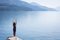 Frau praktiziert Yoga auf Felsen in der Nähe des Meeres — Stockfoto