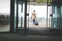 Rückansicht des Geschäftsmannes, der mit Gepäck aus dem Hotel geht — Stockfoto