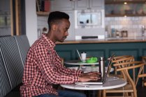 Ejecutiva de oficina masculina usando laptop en cafetería en oficina creativa - foto de stock