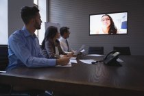 Gli uomini d'affari che conferiscono sullo schermo in sala riunioni in ufficio . — Foto stock