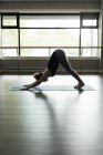 Жінка практикує йогу на тренувальному килимку у фітнес-студії . — стокове фото