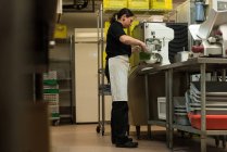 Koch mischt das Essen in der Maschine in der Küche — Stockfoto