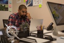 Чоловік-виконавчий розмовляє по телефону, використовуючи ноутбук в офісі — стокове фото