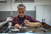 Женщина-работница ремонтирует станок с помощью инструмента на заводе — стоковое фото