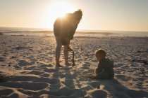 Мати грає з сином на пляжі під час заходу сонця — стокове фото