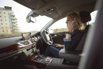 Seitenansicht einer weiblichen Führungskraft, die mit dem Handy im Auto spricht — Stockfoto