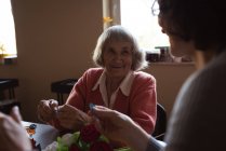 Mujer mayor sonriente interactuando con el cuidador en el hogar de ancianos - foto de stock