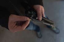 Крупный план человека, загружающего пулю в пистолет — стоковое фото
