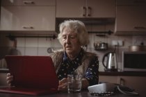 Femme âgée utilisant une tablette numérique dans la cuisine à la maison — Photo de stock