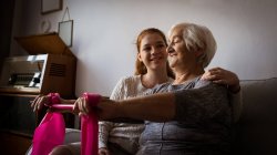 Внучка смотрит на бабушку, выполняющую упражнения в гостиной дома — стоковое фото