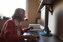 Старшая женщина, работающая за компьютером в доме престарелых — стоковое фото