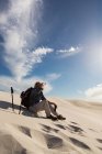 Турист-мужчина смотрит через бинокль на песке в пустыне — стоковое фото