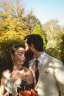 Groom kissing on brides forehead in the garden — Stock Photo