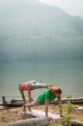Спортивная пара, практикующая акро-йогу на берегу моря в солнечный день — стоковое фото