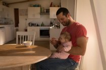 Father feeding baby boy with spoon at home. — Stock Photo